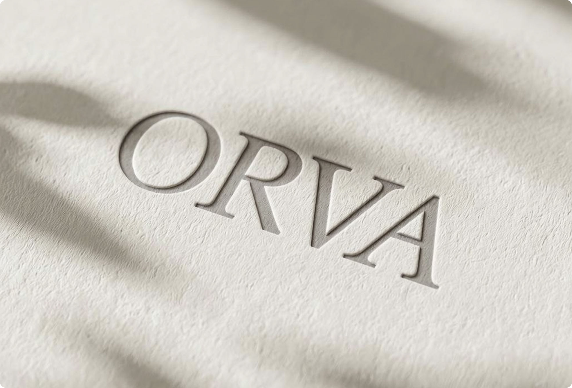Embossed text "ORVA" in elegant serif font on textured, off-white paper, with soft shadows cast across the surface.