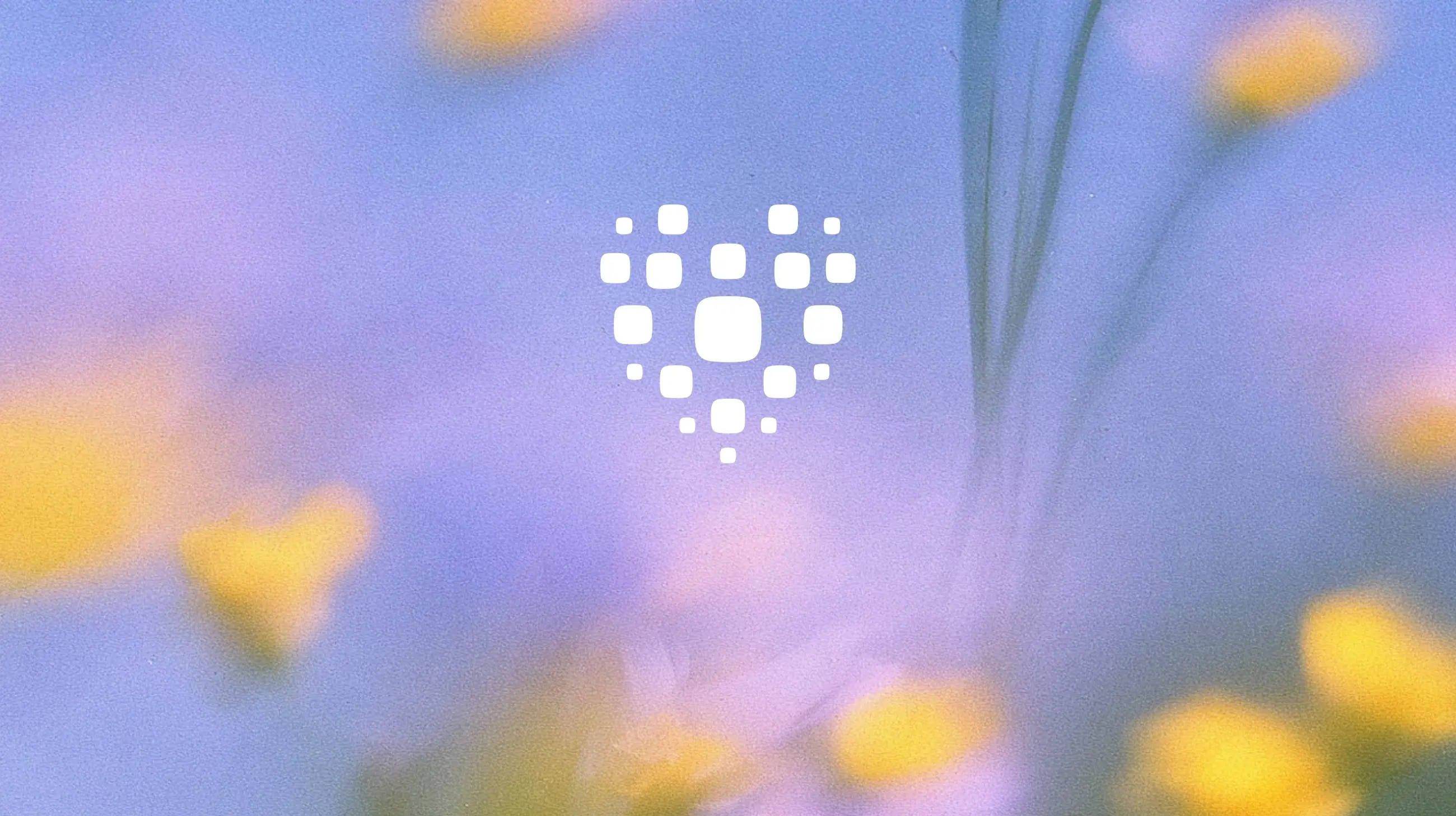 A white logo shaped like a heart made of rounded square dots, centered over a blurred, soft-focus background of blue and yellow colors.